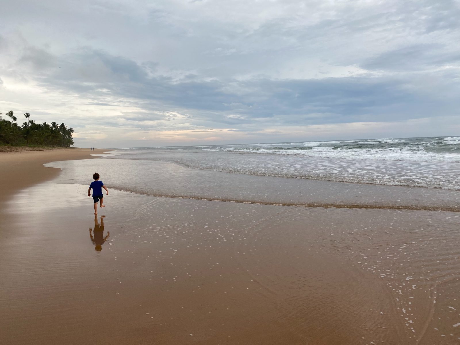 Ein Kind läuft am Strand von Barra Grande über den Sand, mit Blick aufs Meer.